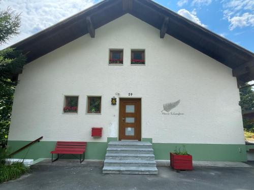 a white building with a red door and two windows at Haus Silverfern in Förolach
