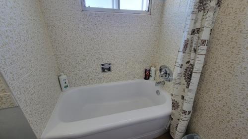 eine weiße Badewanne im Bad mit einem Duschvorhang in der Unterkunft 4-Bedroom Home by Downtown and Airport in Calgary