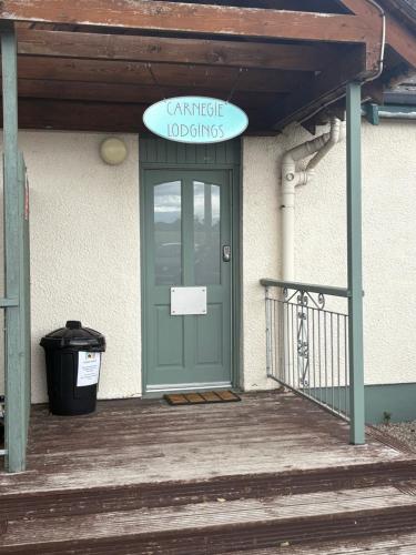 a building with a green door with a sign on it at Carnegie Lodgings, Tain in Tain