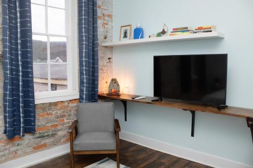 a living room with a television and a chair at Bischoff Inn - Former 1870 Furniture Factory Now 5 Room Boutique Hotel in Tamaqua