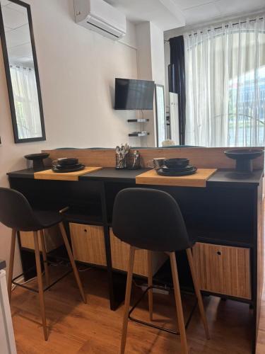 a kitchen with a black counter with two stools at Studio Lent Riverstay in Maribor
