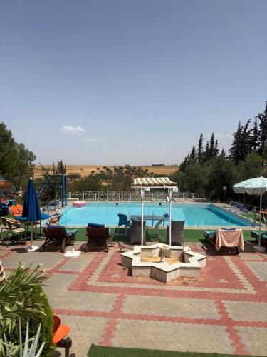 a large swimming pool with tables and chairs next to it at Gîte à la ferme khemissat 