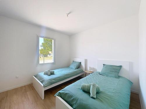 a bedroom with two beds and a window at Entre Terre et Mer in Sallertaine