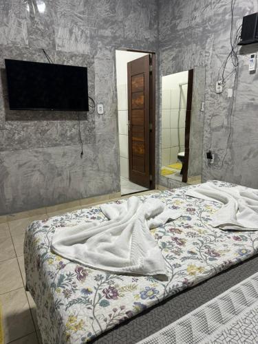 a bed in a room with a tv on a wall at Girassol eventos in Macapá