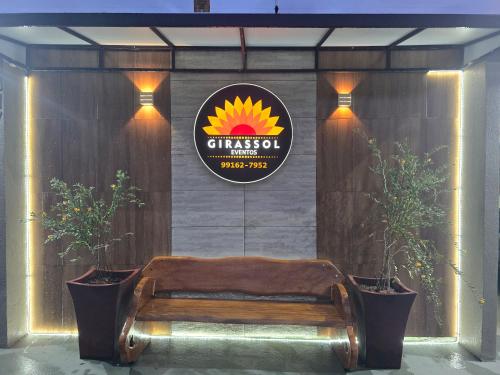 a sign on a wall with a bench and two plants at Girassol eventos in Macapá