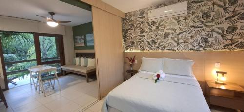 a bedroom with a bed and a table and a chair at Villa do Cajueiro Imbassaí in Imbassai