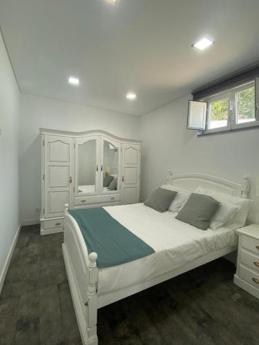 a bedroom with a white bed and a white cabinet at Alex Guest House in Quinta do Anjo