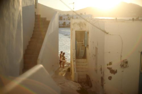 a couple of people walking down a stairs next to the ocean at Naousa's Melody in Naousa