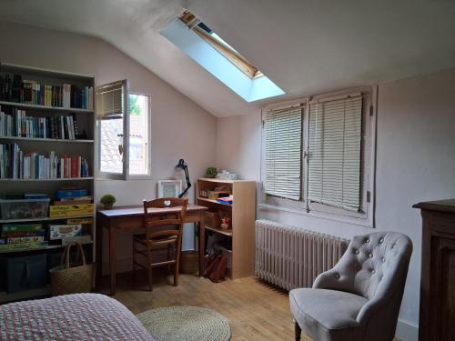 een slaapkamer met een bureau, een stoel en een raam bij Les bananiers in Bergerac