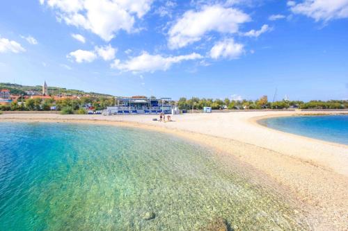 una playa con agua azul y edificios de fondo en B apartment with terrace 1 min walk to the beach, en Supetar