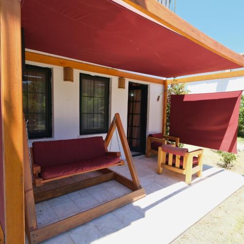 a patio with a red roof and a bench at Club Mel Holiday in Ortaca