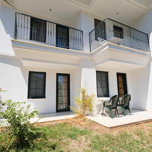 a white house with a balcony and two chairs at Club Mel Holiday in Ortaca