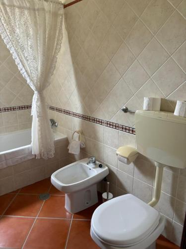 a bathroom with a toilet and a sink and a tub at Casa Oasis - Paraiso na Terra in Tunes