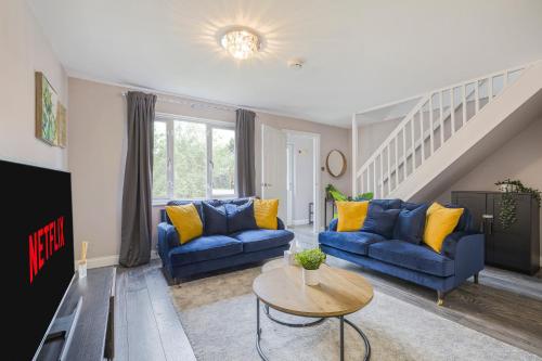 a living room with two blue couches and a table at Stunning Three Bedroom Home Central MK, Pool Table, Free Parking, Smart Tv with Netflix and Disney plus in Shenley Lodge