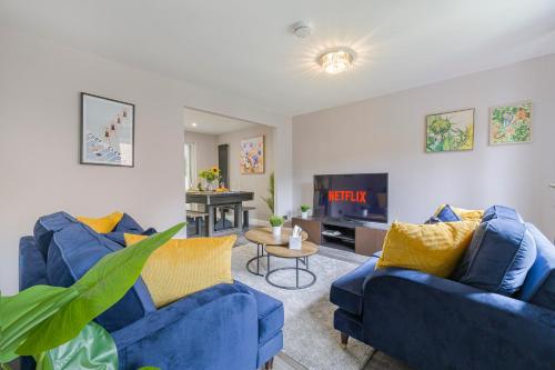 a living room with two blue couches and a tv at Stunning Three Bedroom Home Central MK, Pool Table, Free Parking, Smart Tv with Netflix and Disney plus in Shenley Lodge