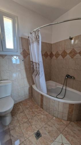 a bathroom with a tub and a toilet and a sink at Alexandras Villa in Skala Marion