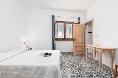 a white bedroom with a bed and a table at Casa Regina Margherita in Loculi
