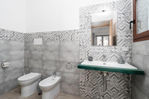 a bathroom with a toilet and a sink and a mirror at Casa Regina Margherita in Loculi