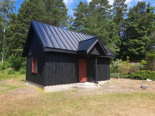 a black shed with a red door in a field at Jauntilmači in Košrags