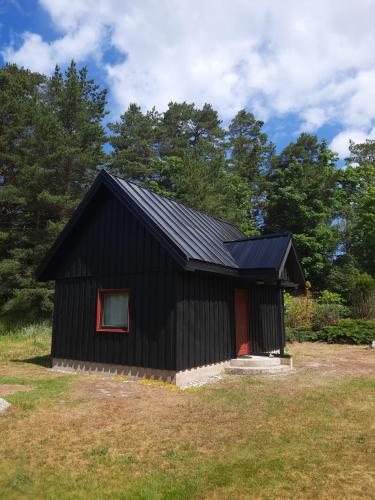 a black house with a red door in a yard at Jauntilmači in Košrags