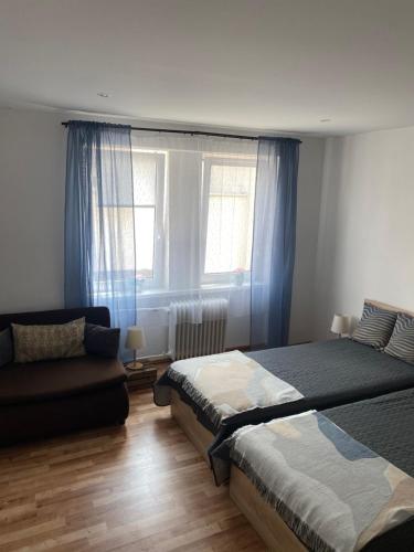 a bedroom with a bed and a couch and a window at Apartmán Centrum in Martin