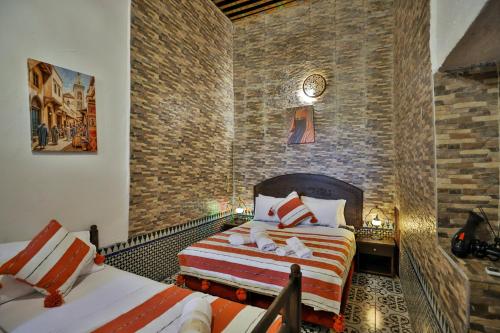 a bedroom with two beds and a brick wall at Riad Fes Zayna in Fès