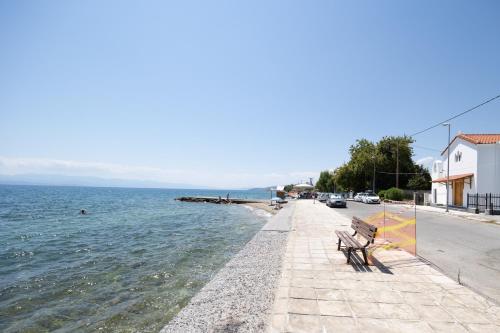 a bench sitting on a sidewalk next to the water at Seabreeze Platanidia in Platanidia