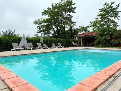 une grande piscine avec des chaises et une maison dans l'établissement Las Coumeilles, à Leychert