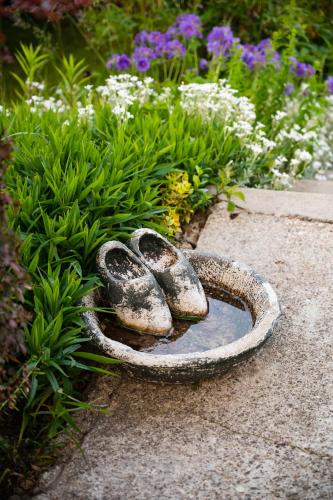 a statue of a bird bath in front of flowers at Heart of Polen appartements in Piechowice