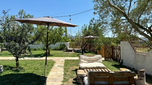 a chair and an umbrella in a yard at Tringa Guesthouse - Mrizi i Zanave in Fishtë