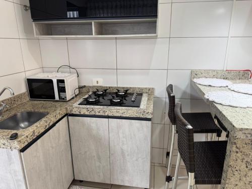 a kitchen with a stove and a microwave at Apartamento maringa in Maringá