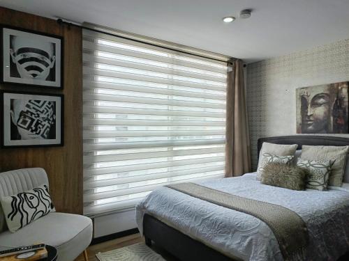 a bedroom with a window with a bed and a chair at Apartment - 2Bedrooms - QueenBed - Balcony - Parking - 7thFLOOR in Quito