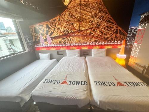 two beds in a room with a tokyo tower at Henn na Hotel Tokyo Hamamatsucho in Tokyo