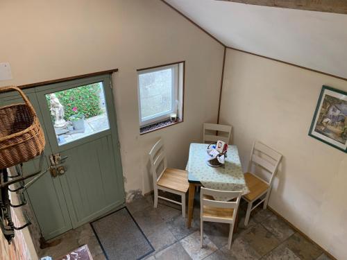 ein Esszimmer mit Tisch und Stühlen und einer Tür in der Unterkunft La Petite Maison, Perrou, Normandy, Orne in Perrou