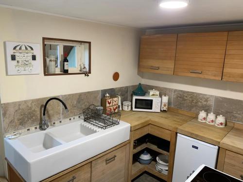 eine Küche mit Spüle und Mikrowelle in der Unterkunft La Petite Maison, Perrou, Normandy, Orne in Perrou