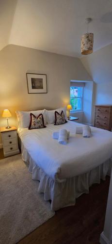 a large white bed in a bedroom with two lamps at Yeomans Cottage in Pitlochry