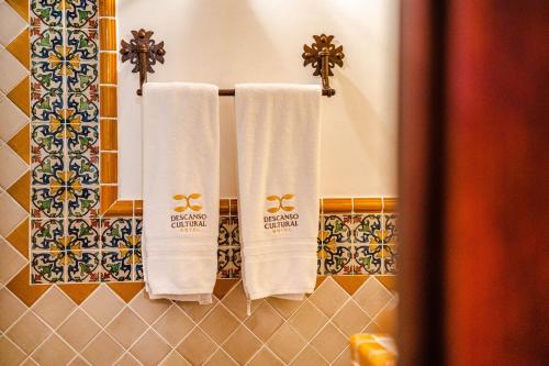 two white towels hanging in a bathroom with tiles at Hotel El Descanso Cultural in Antigua Guatemala