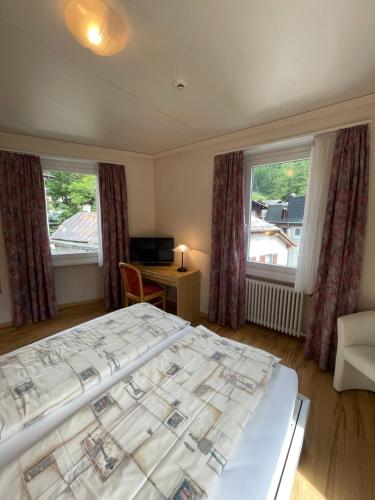 a bedroom with a large bed and two windows at Weisses Rössli in Leukerbad