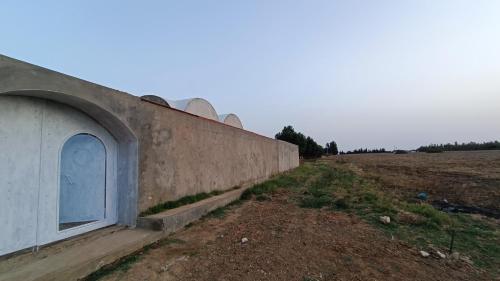 a concrete wall with a blue door next to a field at Maison Sérénité Campagne in Hammamet Sud
