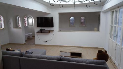a living room with a couch and a flat screen tv at Maison Sérénité Campagne in Hammamet Sud