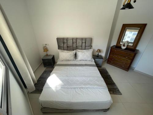 a bedroom with two beds and a dresser and a mirror at Cosy apartment in Bouznika in Bouznika