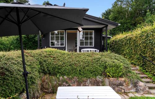 a black umbrella and a bench in front of a house at Pet Friendly Home In Aabenraa With Wifi - F07406 in Aabenraa