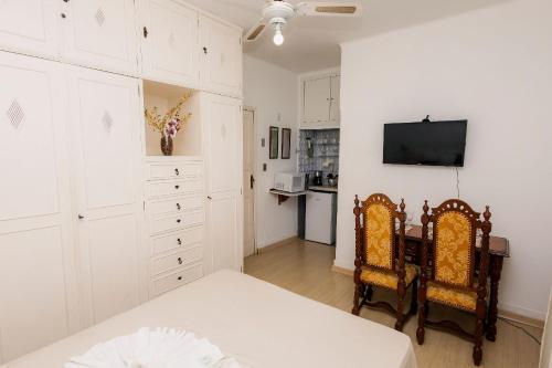a bedroom with a bed and two chairs and a television at Suíte no Centro de Caxambu - Poucos metros do Parque in Caxambu
