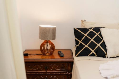 a lamp on a night stand next to a bed at Suíte no Centro de Caxambu - Poucos metros do Parque in Caxambu
