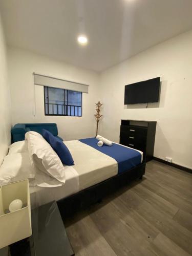 a bedroom with a large bed and a flat screen tv at El Solar Casa Hotel in Manizales