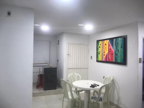 a table and chairs in a room with a painting on the wall at Hostal Jerry Inn in Valledupar