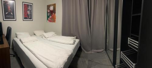 Una cama con sábanas blancas y almohadas en una habitación. en Husafjellet, en Ålesund