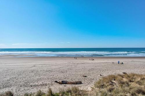 a beach with people on the sand and the ocean at Spacious Beachfront Suite - Sleeps 7 - Second Floor - Pool and Sauna in Lincoln City