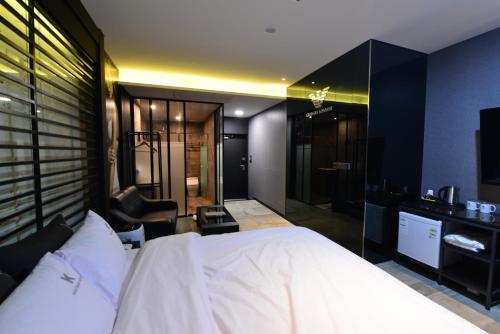 a bedroom with a large white bed and a bathroom at K Boutique Hotel in Yeosu