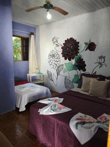 a bedroom with two beds and a flower mural on the wall at Pousada Villa da Música Beira Mar Dàlia Pontal Centro in Paraty